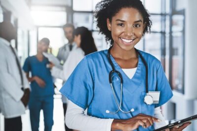 A young doctor in scrubs using a tablet.