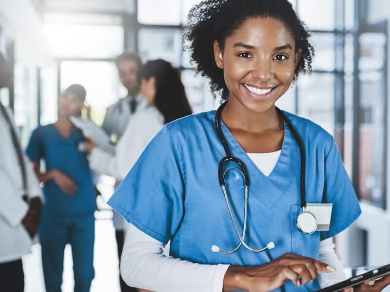 A young doctor in scrubs using a tablet.