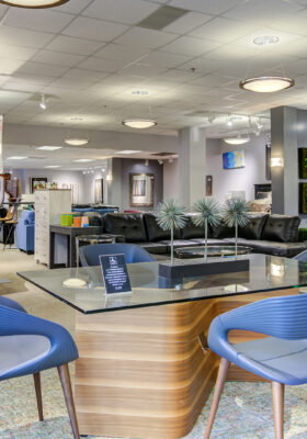 A well-lit furniture showroom featuring a mix of dining tables, chairs, lounge seating, and wall decor, highlighting CORT Furniture Outlet’s variety of stylish furniture.