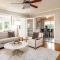 Beautifully curated rental home with furniture rental from CORT Furniture Rental, illustrating why people rent furniture and the benefits of renting furniture. Neutral decor including a couch, armchair, rug, dining set, floor lamp, modern coffee table, and flatscreen TV are visible.