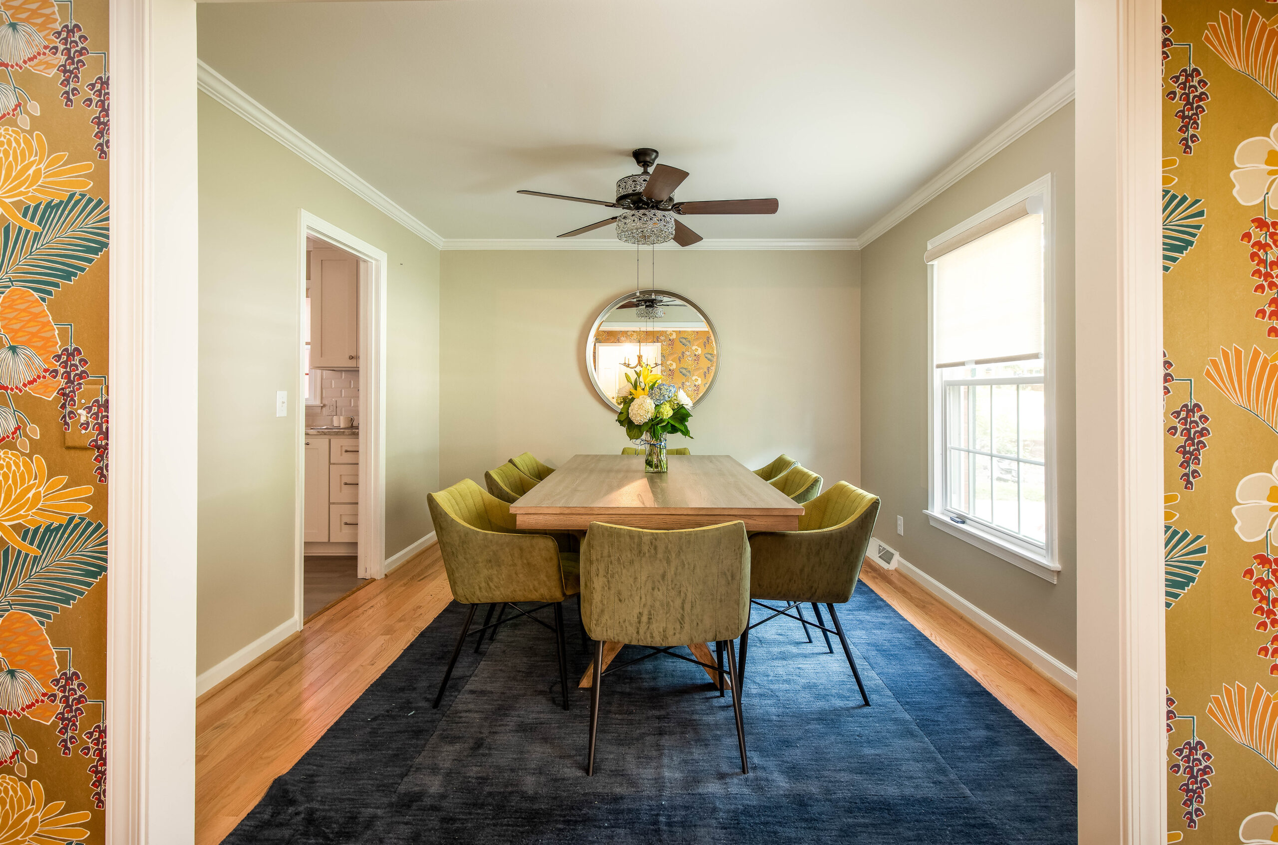 Modern dining room with green velvet chairs and a wood table, styled for a fully furnished rental home