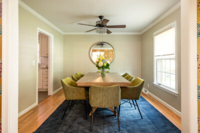 Modern furnished dining room with velvet chairs and fresh flowers, styled for a temporary home