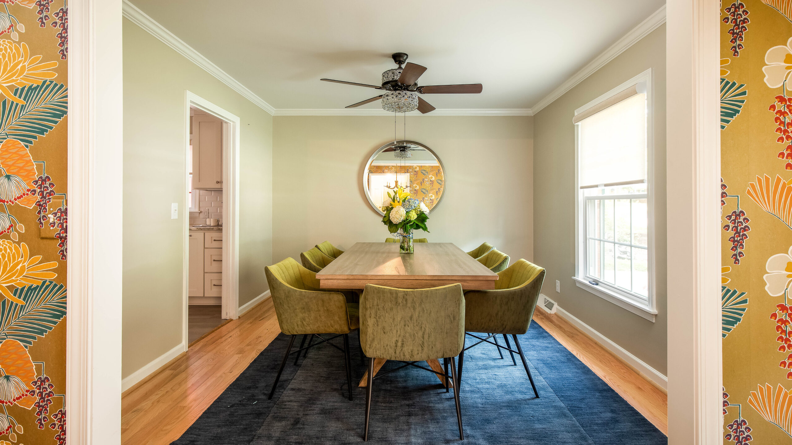 Modern furnished dining room with velvet chairs and fresh flowers, styled for a temporary home