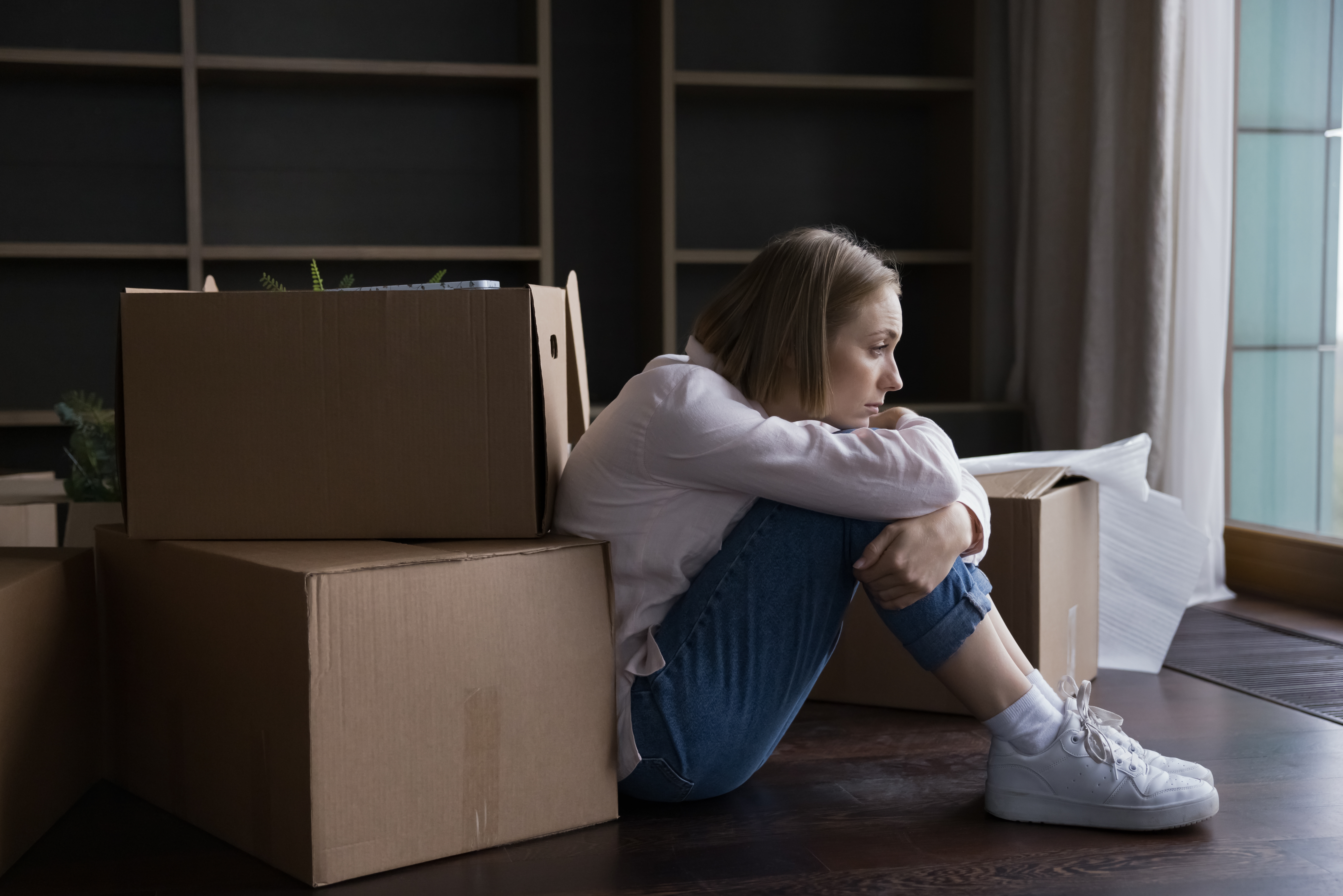 Woman sad on floor because roommates getting house without her.